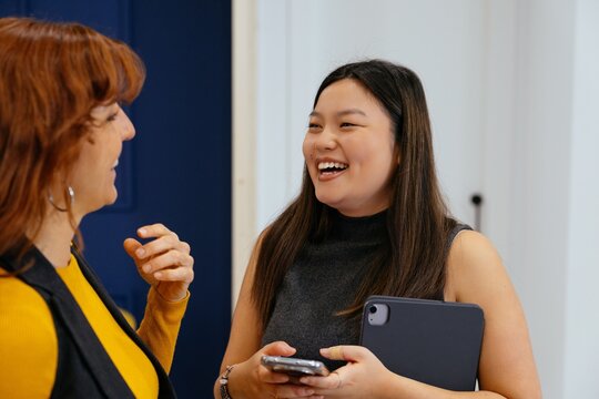 Diverse businesswomen laughing discussing work in office