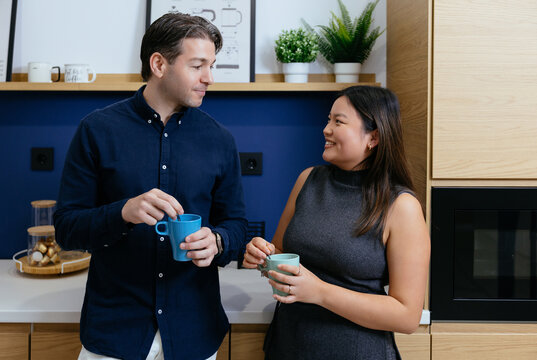 Colleagues drinking coffee and talking in office breakroom