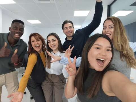 Diverse team of happy employees taking office group selfie