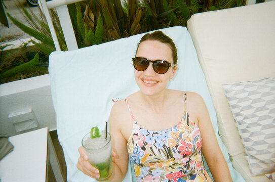 Happy Woman Enjoys Cocktail at Lounger 