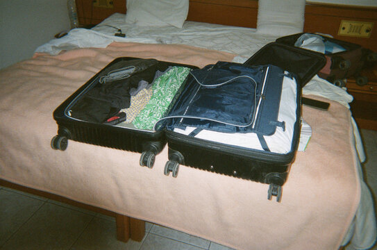 Travel Suitcases Are Packed With Clothes on Hotel Bed