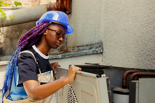 Qualified expert taking apart rusty condenser front grill in order to start reconditioning damaged internal parts. Skilled professional employed by customer to do checkup on hvac system