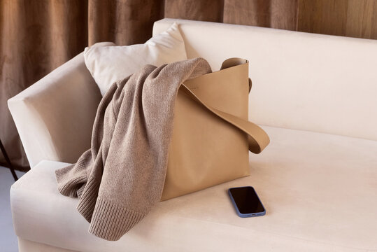 Beige bag with sweater on a sofa