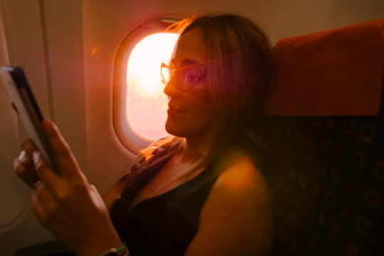 Person Reading on an Airplane During Sunset