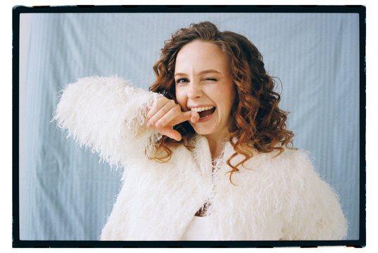 Woman smiles and winks while posing in white coat