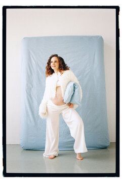 Pregnant person holding belly in home setting