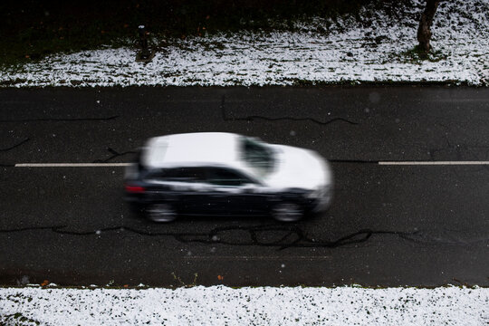 Black Car Driving Through Light Urban Snowfall