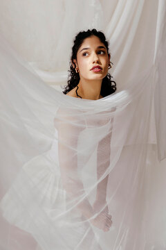 Woman posing gracefully wrapped in flowing white fabric