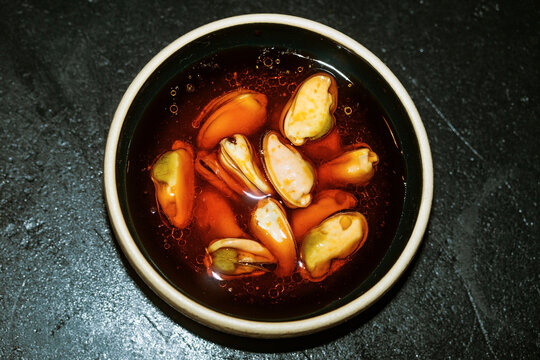 Mussels in Oil Served in a Small Dish on a Dark Surface
