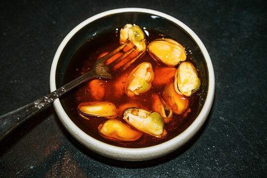 Mussels in Oil Served in a Small Dish on a Dark Surface