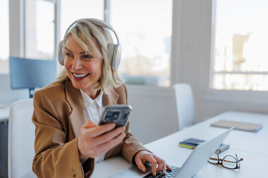 Formal businesswoman multitasking with phone and laptop
