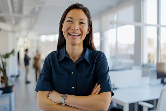 Businesswoman smiling with crossed arms in office