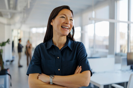 Woman smiling confidently looking away in modern office
