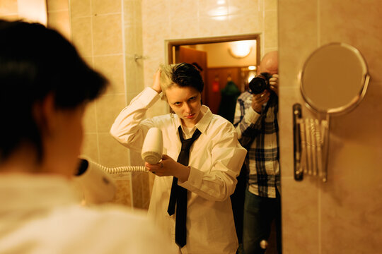 Person Drying Hair in Bathroom While Another Person Takes Photo