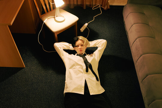 Person Lies on Floor in Room Near Chair and Lamp