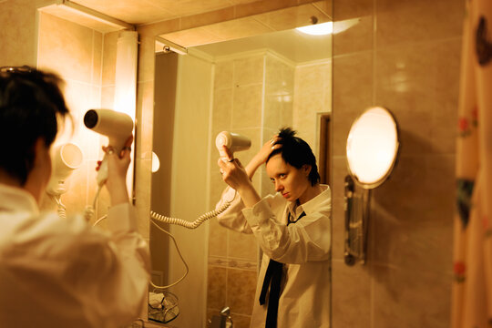 Woman Drying Her Hair in a Bathroom Mirror at Night