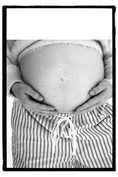 Pregnant person holding belly in home setting