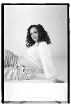 Pregnant woman poses on a white surface