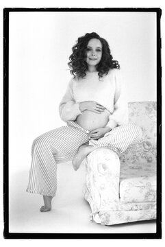 Pregnant woman sits on a chair with joy