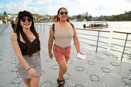 Two young women walking on a floating dock in guatape