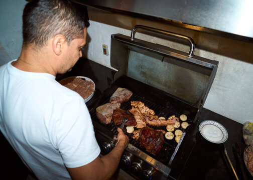 Man cooking, grilling meat and vegetables showing culinary skill