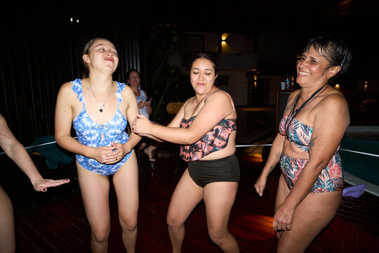 Women dancing and laughing at nighttime pool party