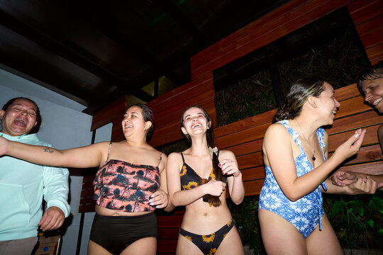 Group of women laughing and having fun at night pool party