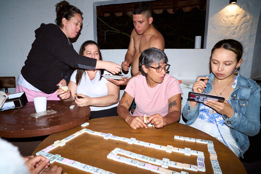 Family and friends playing dominoes game, eating snacks
