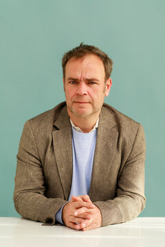  Man Sitting at a Table With a Plain Background
