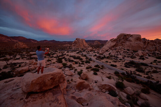 Man captures the serene beauty of a desert landscape as the sun sets