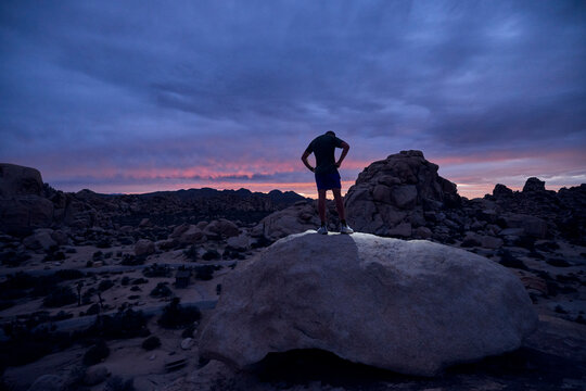 Person Stands on Rock at Sunset in Desert Landscape