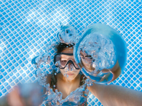 Underwater self portrait of a girl in diving goggles and with bubbles