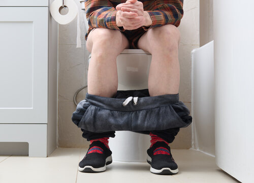 Woman Sitting Patiently on Toilet Lower Body