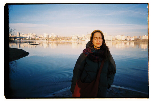 Woman enjoying winter sun by city river waterfront