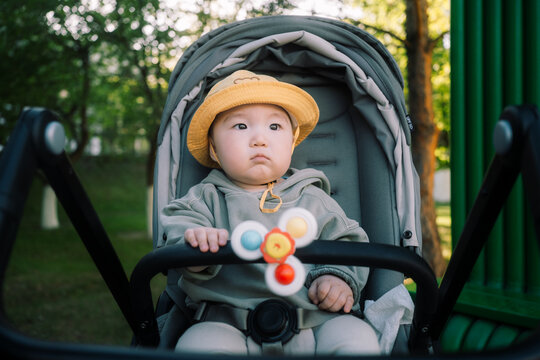Baby in Stroller Wearing Yellow Hat in Green Park