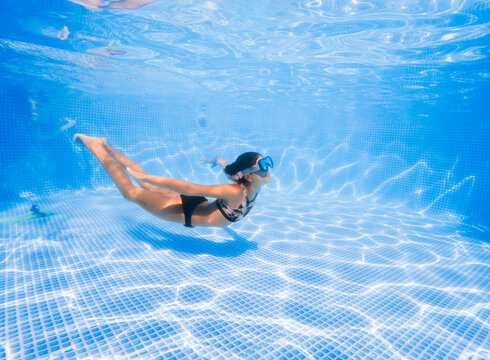 Girl diving and doing acrobatic exercises in a pool. 