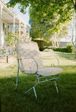 Old Chair Sits in a Grassy Yard Outside a House Under a Tree