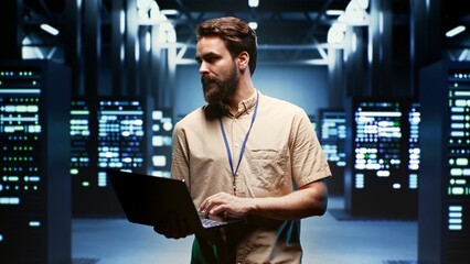 Obraz na płótnie Canvas Engineer using laptop to monitor energy consumption across server components and distributors. Expert ensuring data center sensors for temperature and humidity are functioning optimally