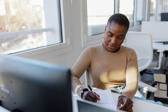Woman writing paperwork in modern office