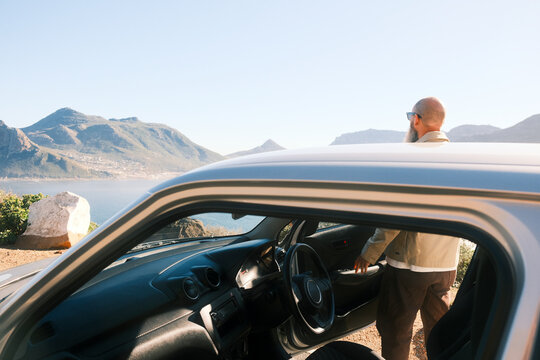 Bearded man wearing sunglasses standing behind car in Cape Town
