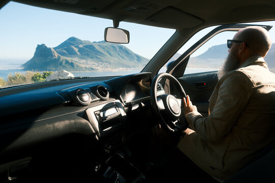 Bearded man driving car along coastal road in Cape Town