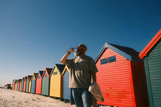 Bearded man drinking water at Muizenberg beach huts