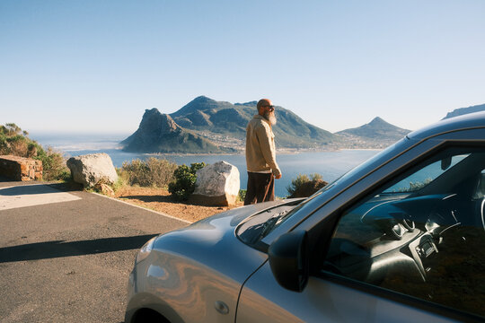 Bearded man wearing sunglasses standing behind car in Cape Town
