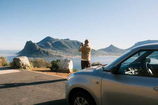 Bearded man taking photo of coastal landscape in Cape Town
