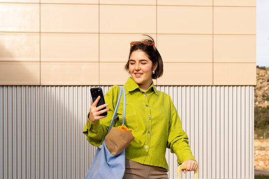 Young woman smiles while using smartphone in vibrant urban setting