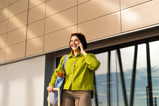 Smiling woman talking on phone while standing outside building