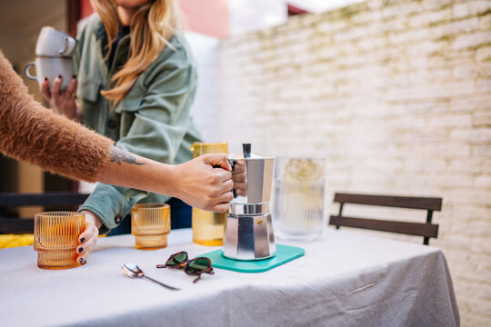Friends preparing coffee on a terrace for social gathering