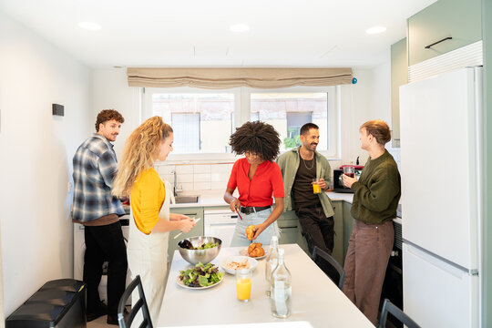 Diverse friends cooking and talking in shared kitchen