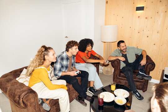 Diverse friends enjoying video gaming together at home