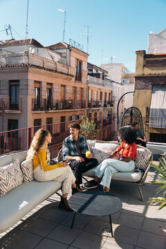 Friends socializing on city rooftop terrace in sunlight